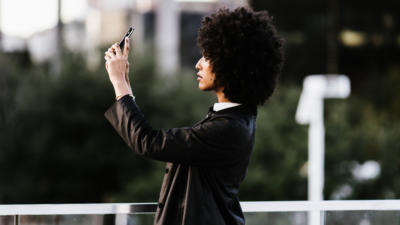 side profile of woman holding phone in the air taking photo